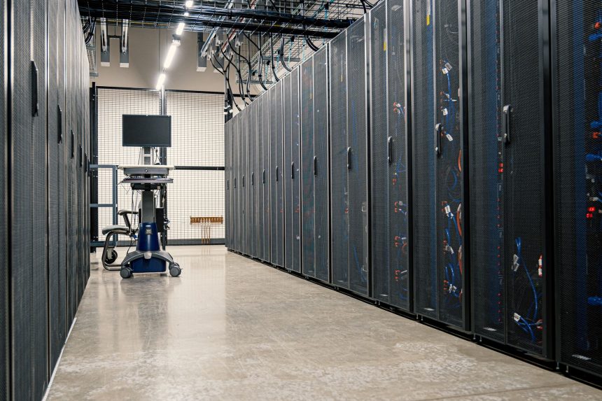 Gabinetes metálicos com servidores, equipamentos de rede e cabos em um data center moderno.