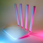Roteador sem fio iluminado por luzes neon em uma composição tecnológica.