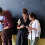 Grupo diverso de jovens adultos usando smartphones em um ambiente interno descontraído