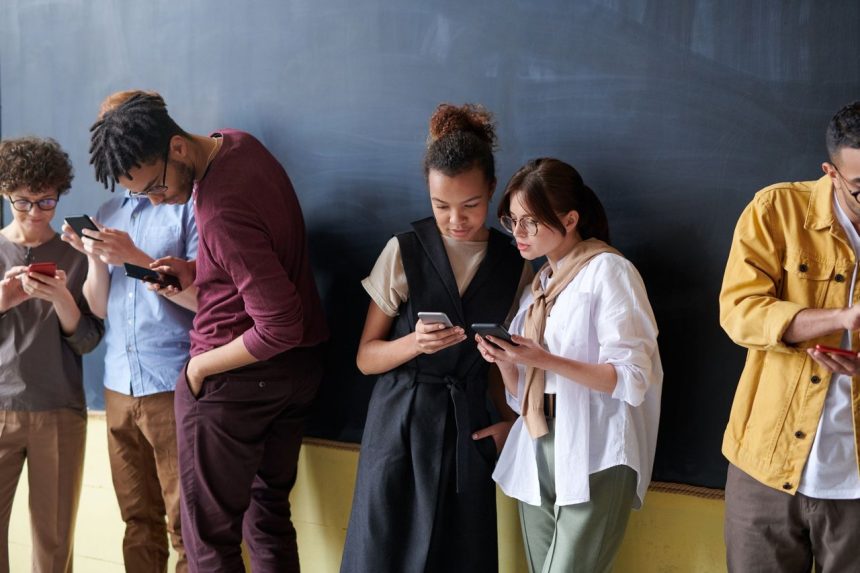 Grupo diverso de jovens adultos usando smartphones em um ambiente interno descontraído