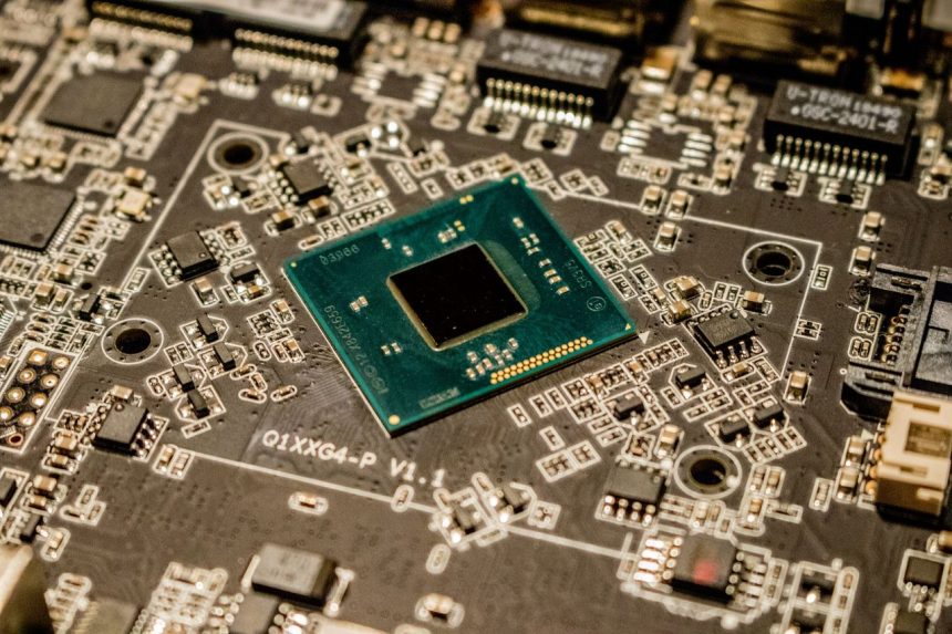 Close de um microchip montado em uma placa de circuito impresso, com componentes eletrônicos visíveis.
