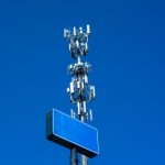 Torre de telecomunicações equipada com diversas antenas contra um céu azul claro
